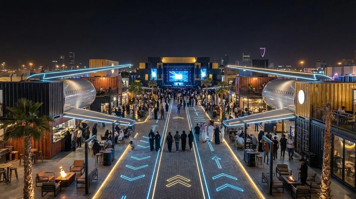 Concept render of the boulevard at night, lit by blue runway lines, with crowds walking towards a stage